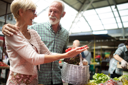 Smiling senior couple buying vegetables and at the merketの写真素材
