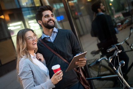 Young couple smiling and using technology in cityの写真素材