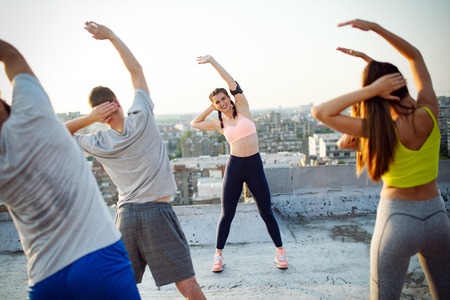 Group of happy fit friends exercising outdoor in city