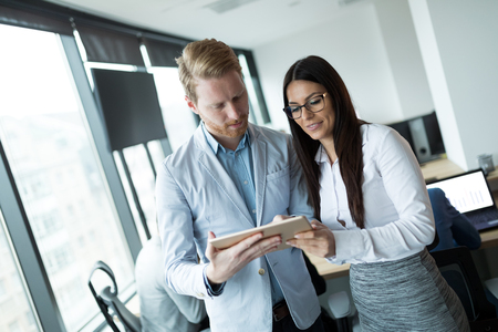Businesspeople discussing while using digital tablet in officeの写真素材