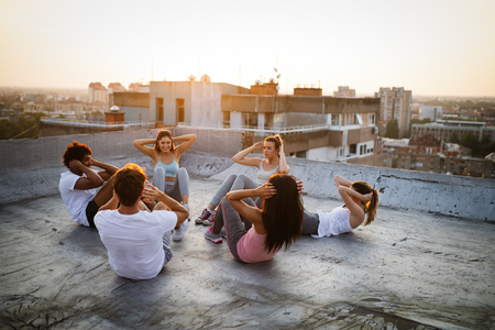 Group of young happy people friends exercising outdoors at sunset.の写真素材