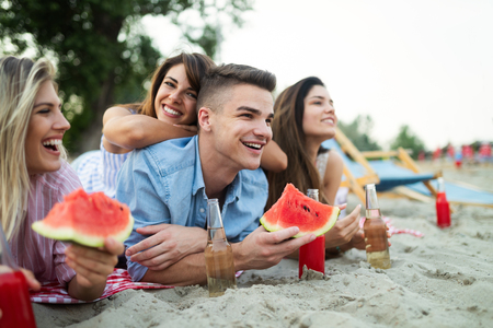 Happy young friends having fun on the beach and eating watermelon.の写真素材