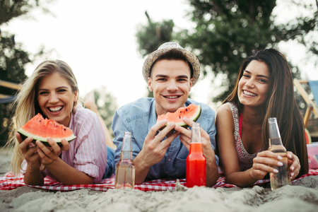 Happy friends having fun on the beach and eating watermelon.の写真素材