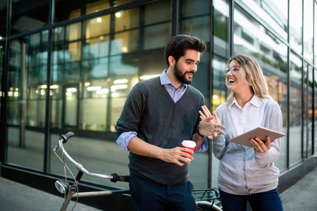 Young couple smiling and using technology in cityの写真素材