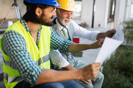 Confident team of architects and engineers working together on construction siteの写真素材