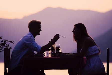 Couple sharing romantic sunset dinner on the beachの写真素材