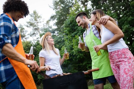 Group of happy friends eating and drinking beers at barbecue dinnerの写真素材