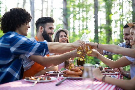 Happy friends camping and having a barbecue in nature