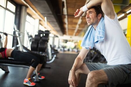 Young fit handsome man doing exercises in gymの写真素材