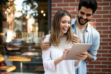 Cheerful happy couple using digital tablet outdoorsの写真素材