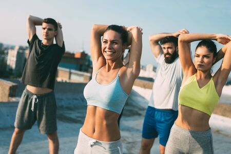 Group of happy fit young people friends in sportswear doing exercises . Sport outdoorsの写真素材
