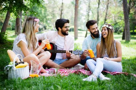 Happy friends in the park having picnic on a sunny day.の写真素材