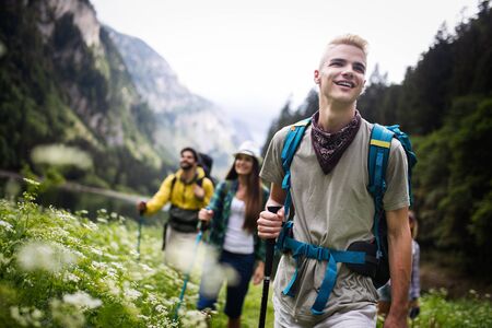 Hiking with friends is so fun. Group of young people with backpacks hiking togetherの写真素材