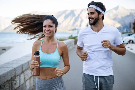 Happy young fit people couple running outdoorの写真素材