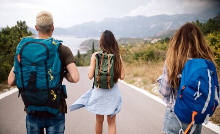Group of friends with backpacks at summer outdoor.