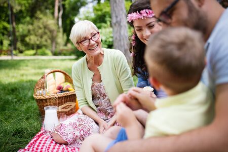 Happy young family playing on the grass in the park and enjoying picnicの写真素材