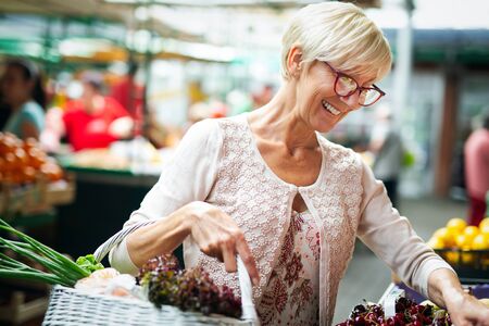 Picture of mature woman at marketplace buying vegetablesの写真素材