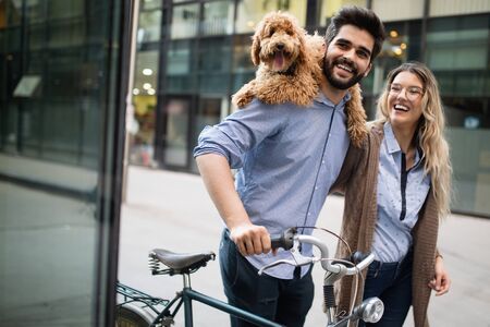 Beautiful couple walking dogs and bicycles outdoors in cityの写真素材