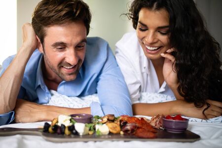 Happy young couple eat breakfast in bedroom in morningの写真素材