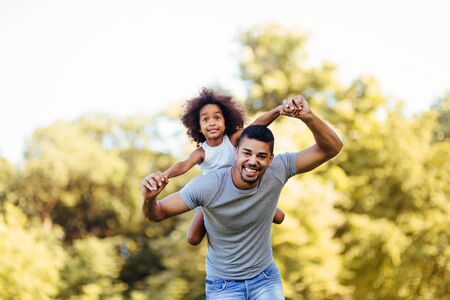 Portrait of young father carrying his daughter on his backの写真素材