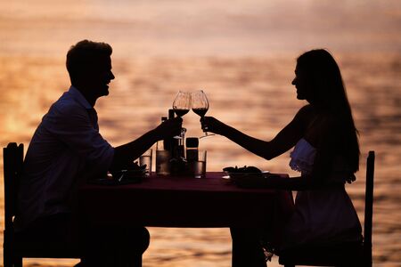 Couple sharing romantic sunset dinner on the beachの写真素材