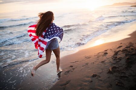 Happy woman running on beach while celebrateing independence day and enjoying freedom in USAの写真素材