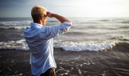 Handsome happy man wearing white shirt at the sea or the ocean backgroundの写真素材