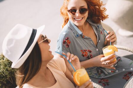 Friends having a great time in cafe. Women smiling and drinking juice and enjoying togetherの写真素材