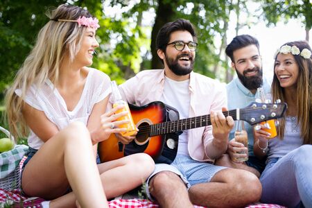 Happy young friends having picnic in the parkの写真素材