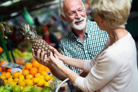 Only the best fruits and vegetables. Beautiful senior couple buying fresh food on marketの写真素材