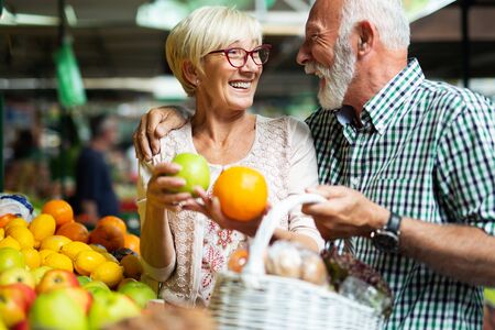 Only the best fruits and vegetables. Beautiful senior couple buying fresh food on marketの写真素材