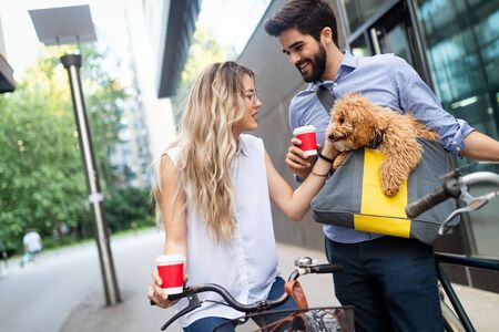 Beautiful couple walking dogs and bicycles outdoors in cityの写真素材