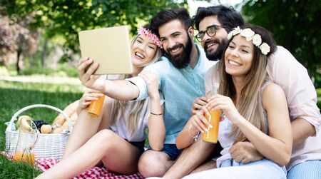 Happy young friends taking selfies on a picnic outdoor