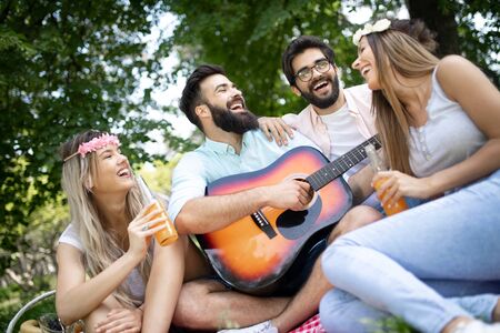 Happy young friends having picnic in the park