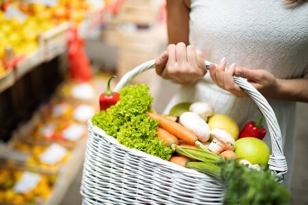Young woman buying vegetable on stall at the marketの写真素材