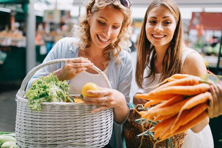 Beautiful happy women shopping vegetables and fruitsの写真素材