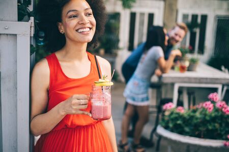 Summer lifestyle fashion portrait of stylish black woman with drinkの写真素材