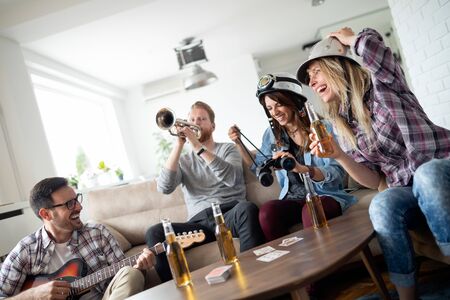 Group of friends at home enjoying singing and playing guitar