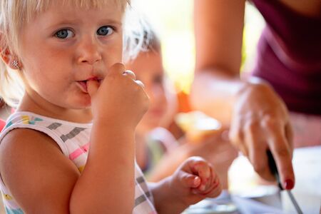 Beautiful kid biting her nails, sucking her fingers witch is not hygienicの写真素材