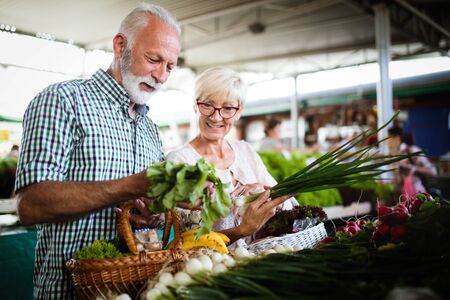 Mature couple shopping vegetables and fruits on the market. Healthy diet.