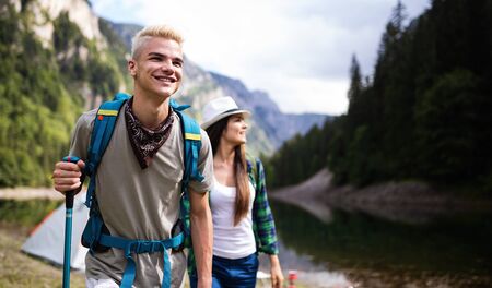 Smiling friends walking with backpacks. Adventure, travel, tourism, hike and people concept.の写真素材