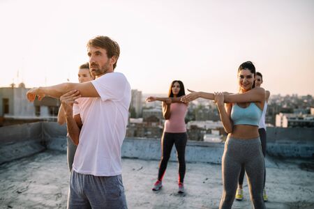 Group of young happy people friends exercising outdoors at sunset.の写真素材