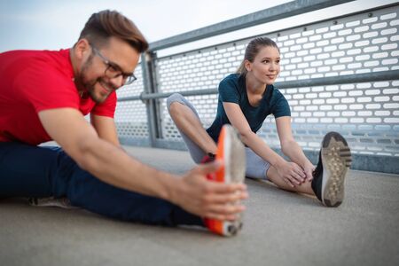 Fitness, sport, training and lifestyle concept. Fit couple friends stretching outdoors