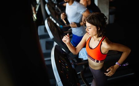Young people running on a treadmill in modern gym