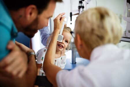 Ophthalmologist is checking the eye vision of little cute girl in modern clinic.の写真素材