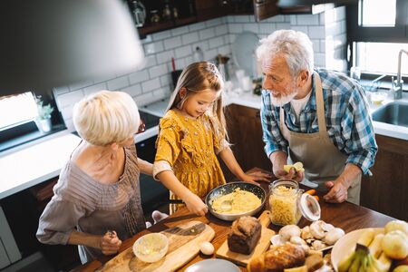 Happy grandparents with grandchildren making breakfast in kitchen