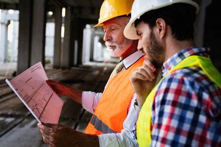 Male architects analyzing blueprint at construction siteの写真素材