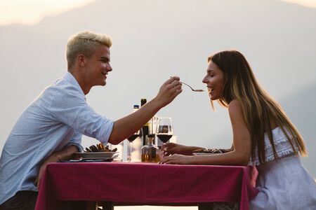 Happy couple on summer evening having romantic dinner outdoorの写真素材