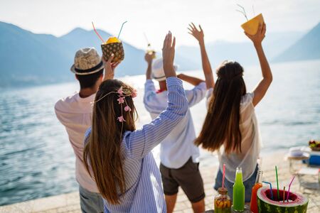 Young group of friends enjoying summer on the beach at sunsetの写真素材