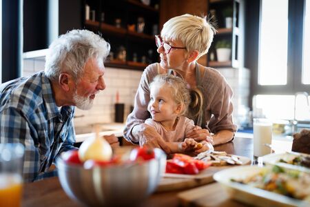 Happy grandparents with grandchildren making breakfast in kitchen